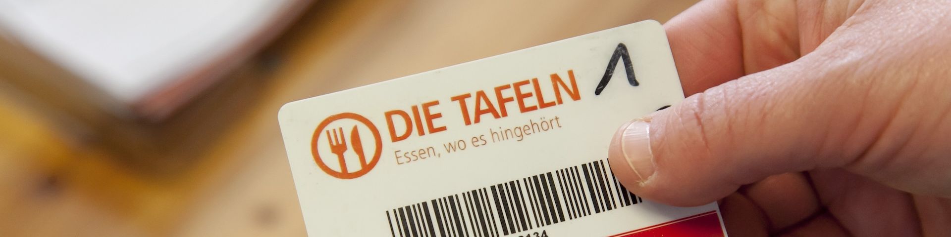 Eine Hand hält den Berechtigungsausweis der Tafel in die Kamera.